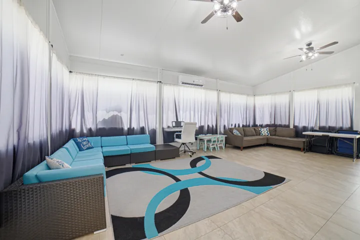 Spacious room featuring light-toned tile flooring, a vaulted ceiling, and multiple ceiling fans