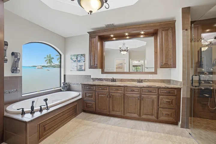 Spacious bathroom featuring a built-in soaking tub beneath an arched window