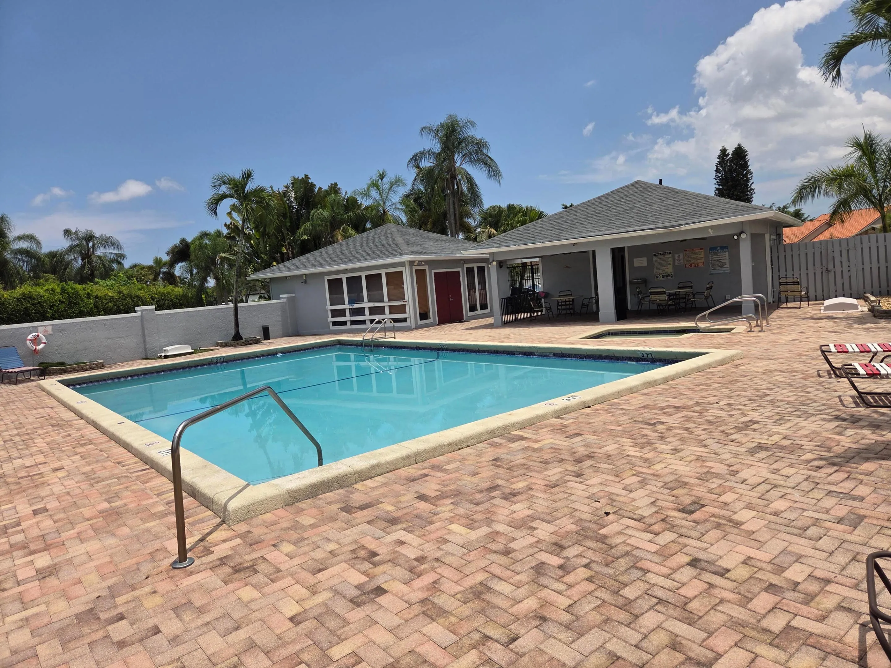 Lakeside heated pool and spa with community room in background and covered gathering place