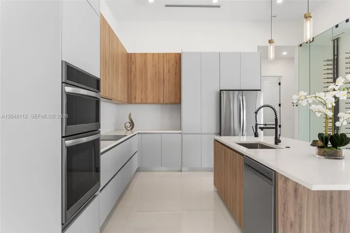 The EXPANSIVE ISLAND offers FLEXIBLE SEATING for CASUAL DINING or FORMAL GATHERINGS, and a FULL QUARTZ BACKSPLASH adds MODERN SOPHISTICATION
