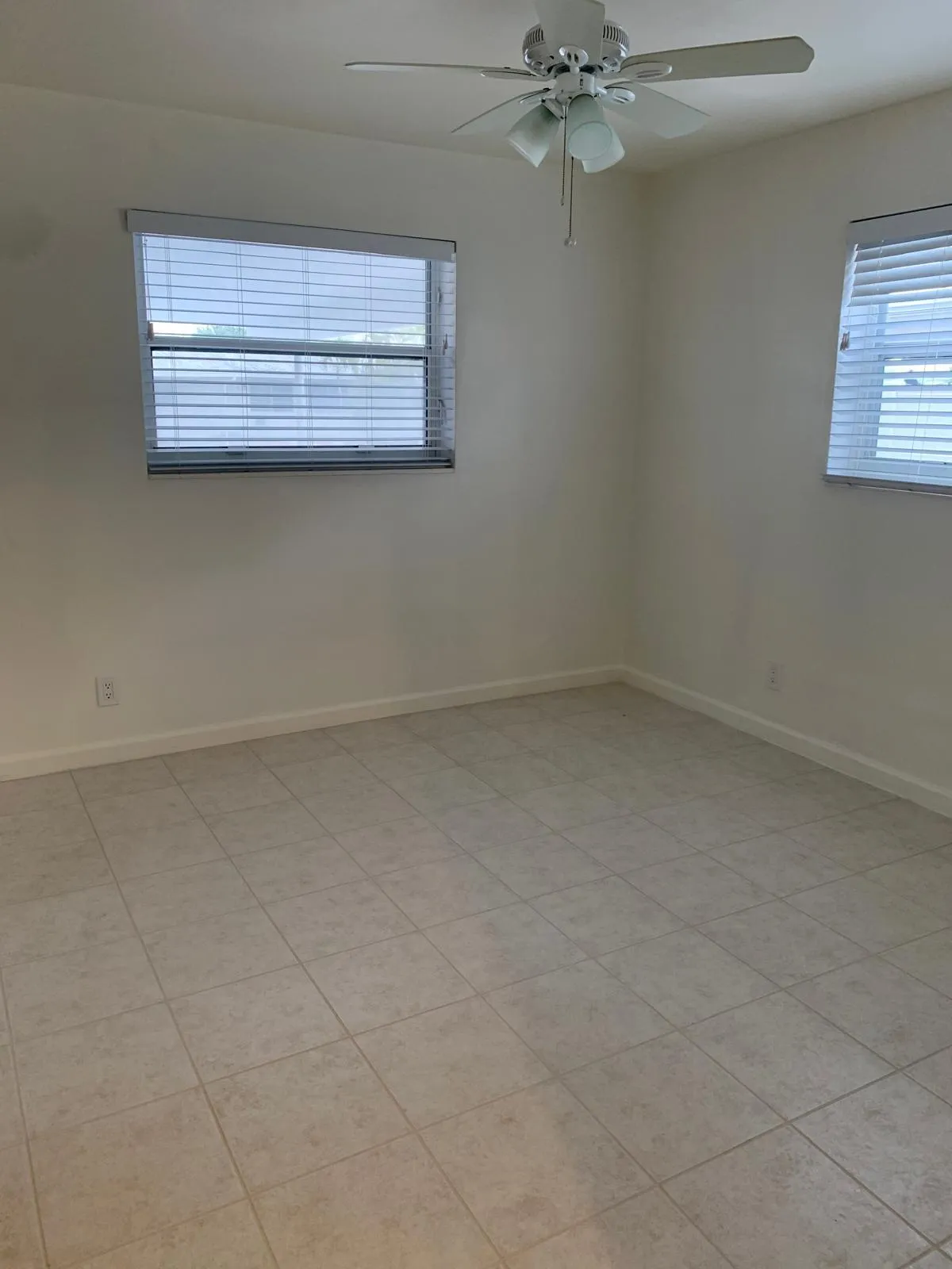 Neutral-toned tiled flooring throughout this bright room featuring a ceiling fan with integrated lighting