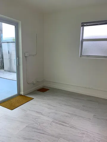 Interior room featuring light-toned walls, a single window with frosted glass, and a glass sliding door