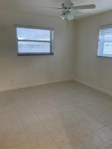 Neutral-toned tiled flooring throughout this bright room featuring a ceiling fan with integrated lighting