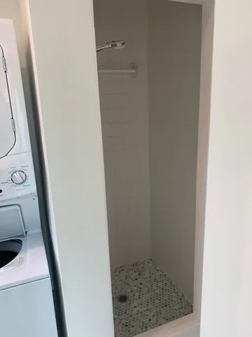Walk-in shower with mosaic tile flooring and white subway tile walls