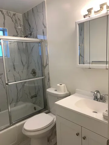 Bathroom featuring a white vanity with integrated sink, chrome faucet, and a wall-mounted medicine cabinet with a three-light fixture