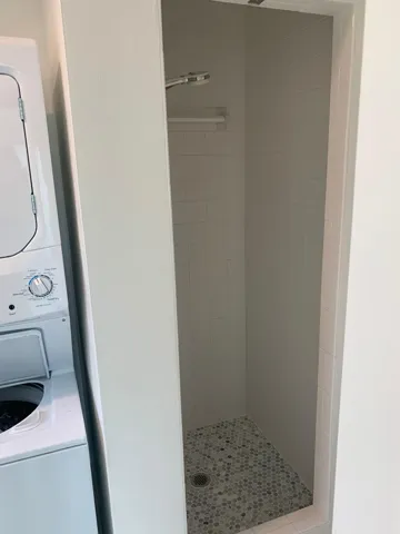 Tiled shower stall featuring a rainfall showerhead, white subway tile walls, and a mosaic tile floor