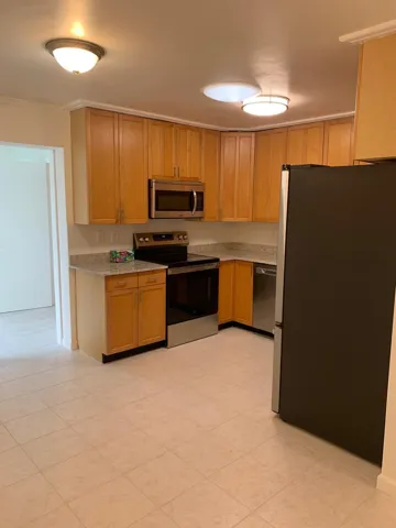 Kitchen featuring light wood-finish cabinetry, solid surface countertops, and tile flooring