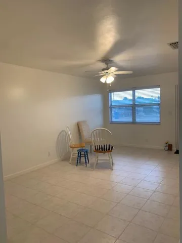 Room featuring light-toned tile flooring, neutral wall finishes, and a ceiling fan with integrated lighting