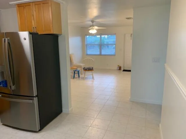 Kitchen area featuring wood cabinetry over a stainless steel refrigerator