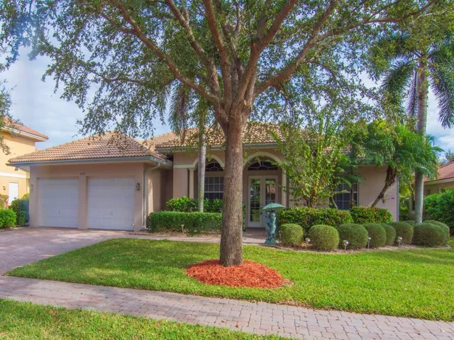 View of front facade featuring french doors, stucco siding, decorative driveway, and a front yard