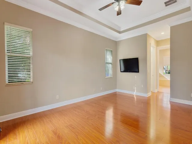 Unfurnished room with wood finished floors, crown molding, a tray ceiling, and ceiling fan