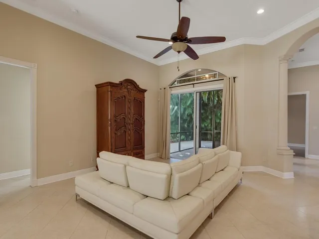 Living room featuring french doors, arched walkways, crown molding, ornate columns, and light tile patterned floors