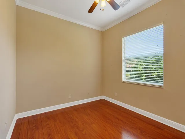 Unfurnished room with light wood-style floors, ornamental molding, a ceiling fan, and a tray ceiling