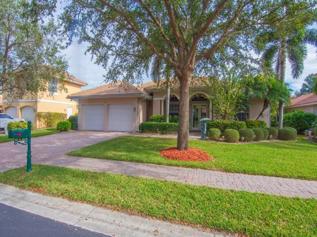 View of front facade featuring french doors, stucco siding, decorative driveway, and a front yard
