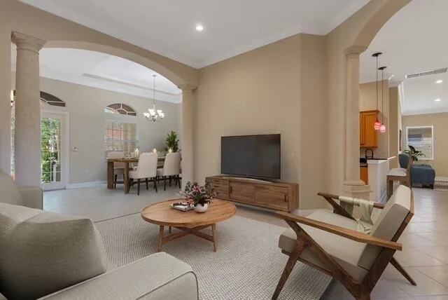 Living room featuring decorative columns, ornamental molding, recessed lighting, and a chandelier