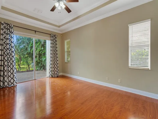 Unfurnished room with wood finished floors, crown molding, a tray ceiling, and ceiling fan