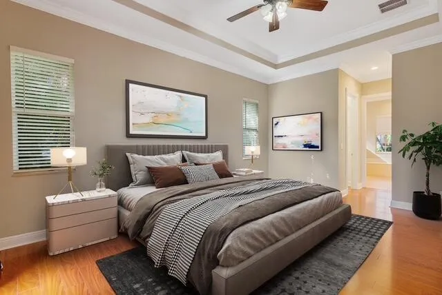 Bedroom with access to exterior, dark wood-style flooring, a tray ceiling, crown molding, and ceiling fan
