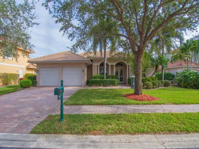 View of front facade featuring french doors, stucco siding, decorative driveway, and a front yard