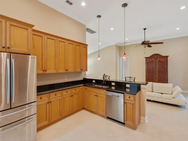 Kitchen with crown molding, a kitchen breakfast bar, decorative light fixtures, light tile patterned flooring, and dark stone countertops