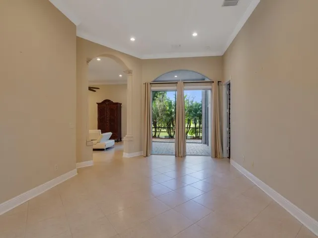 Living room featuring french doors, arched walkways, crown molding, ornate columns, and light tile patterned floors