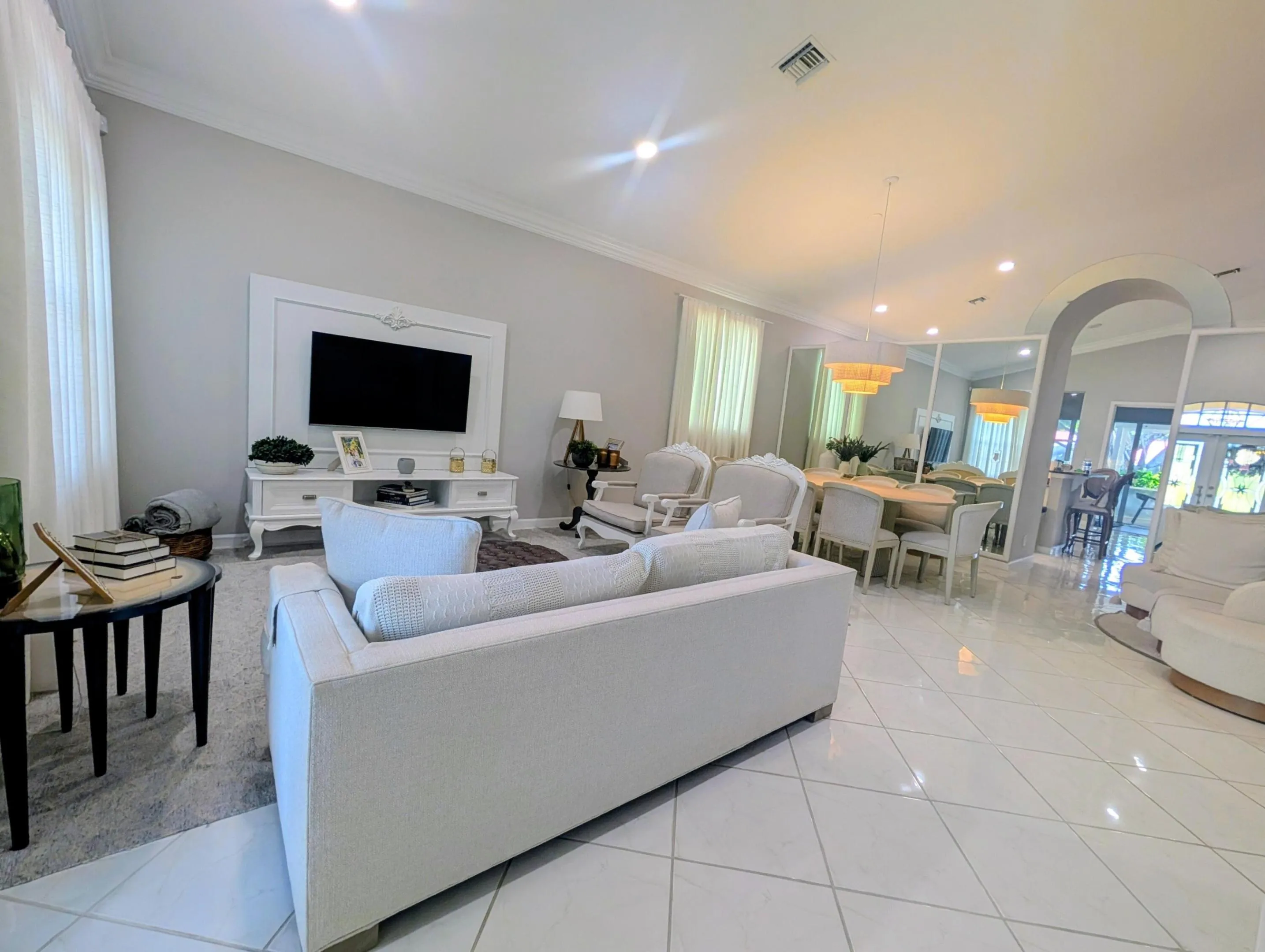 Expansive living area featuring white tile flooring, vaulted ceilings, and crown molding
