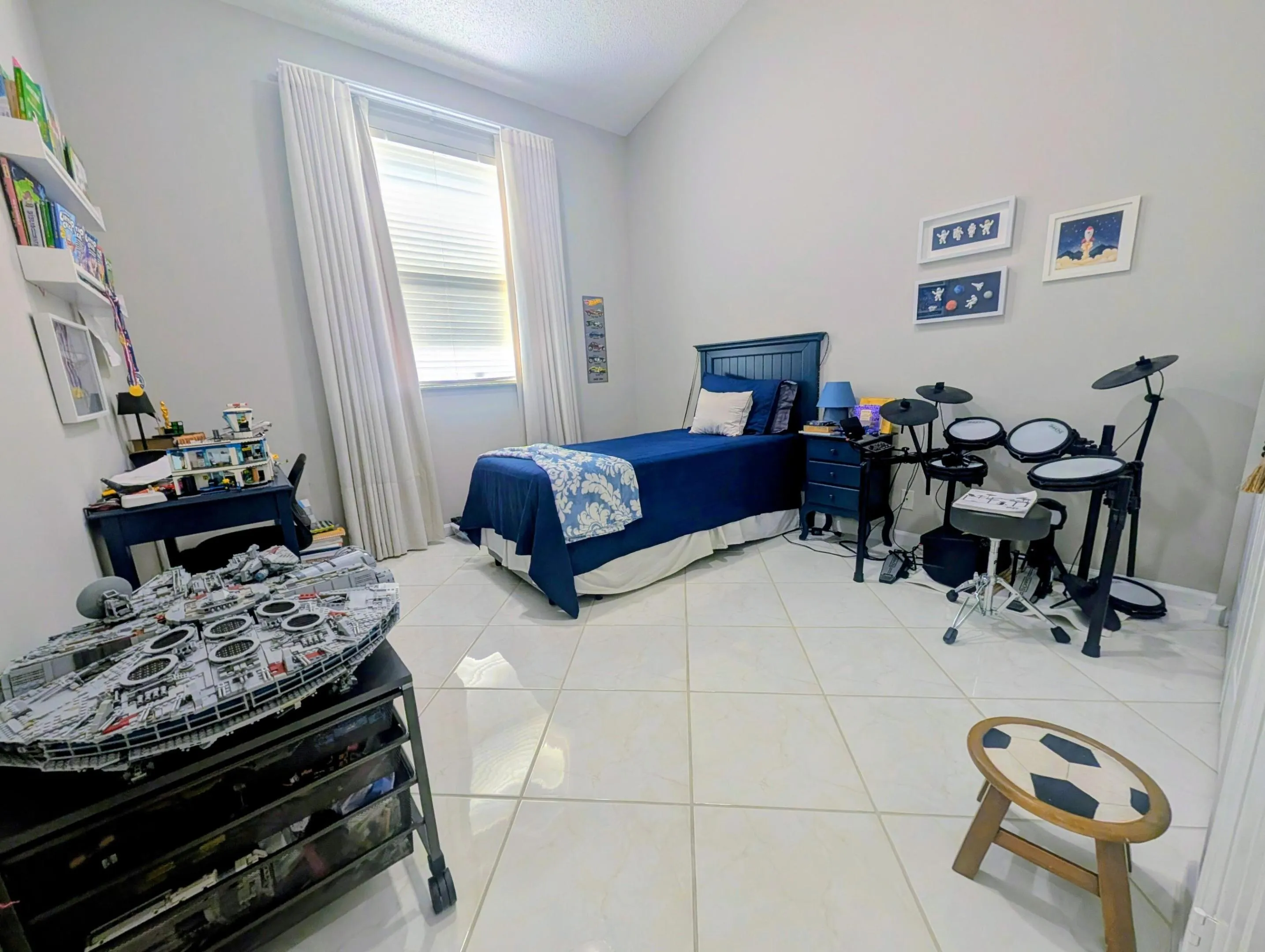 Spacious room featuring vaulted ceilings, a large window with blinds and full-length drapes, and light-toned tile flooring