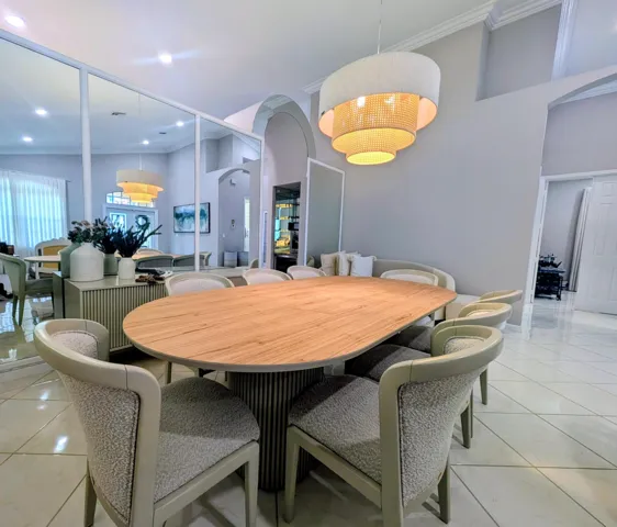 Dining area expansive mirrored wall, vaulted ceiling, and light-toned tile flooring