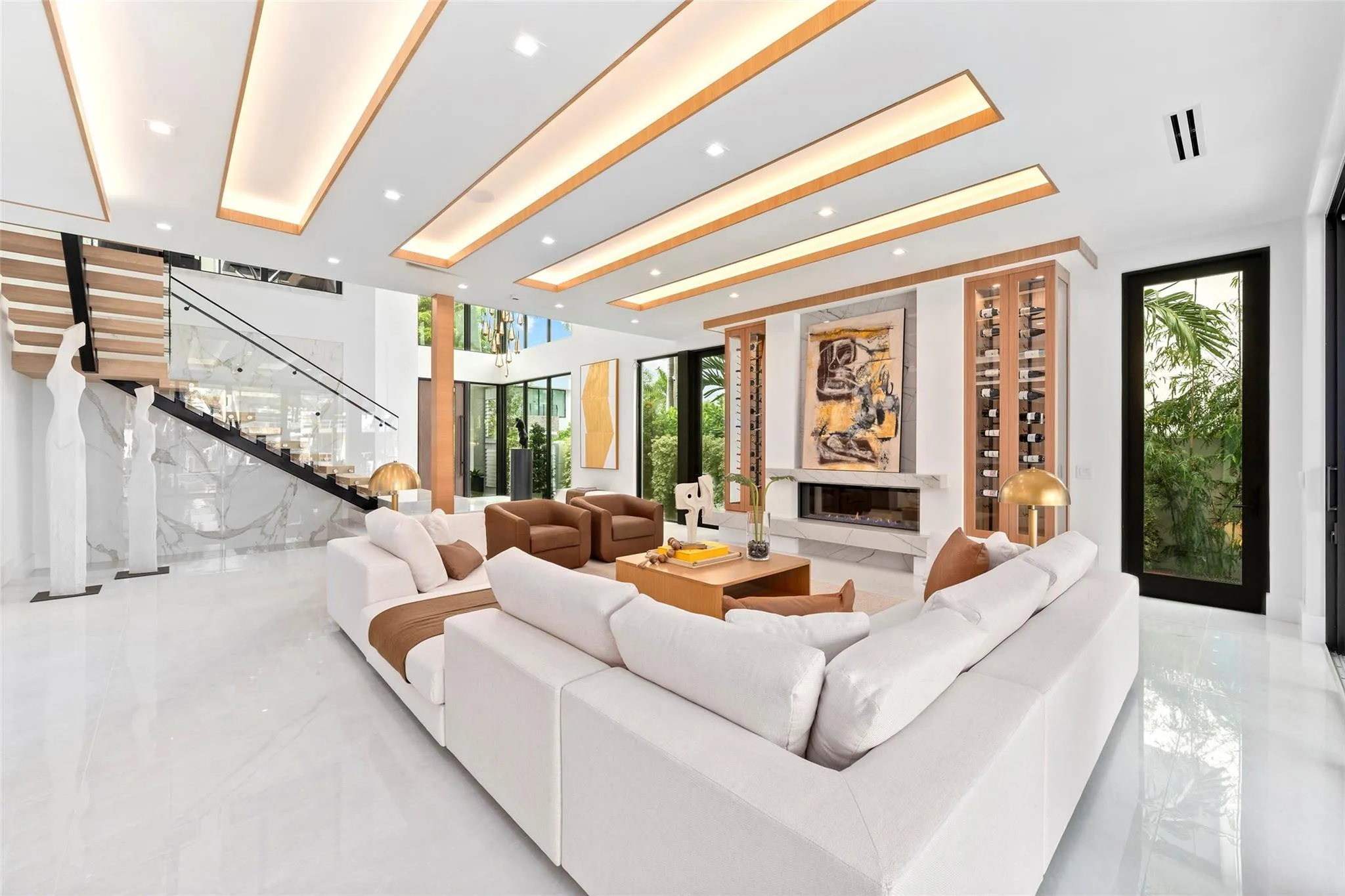 Grand open living space with soaring ceilings, breathtaking water views, a statement fireplace, and custom wine storage.