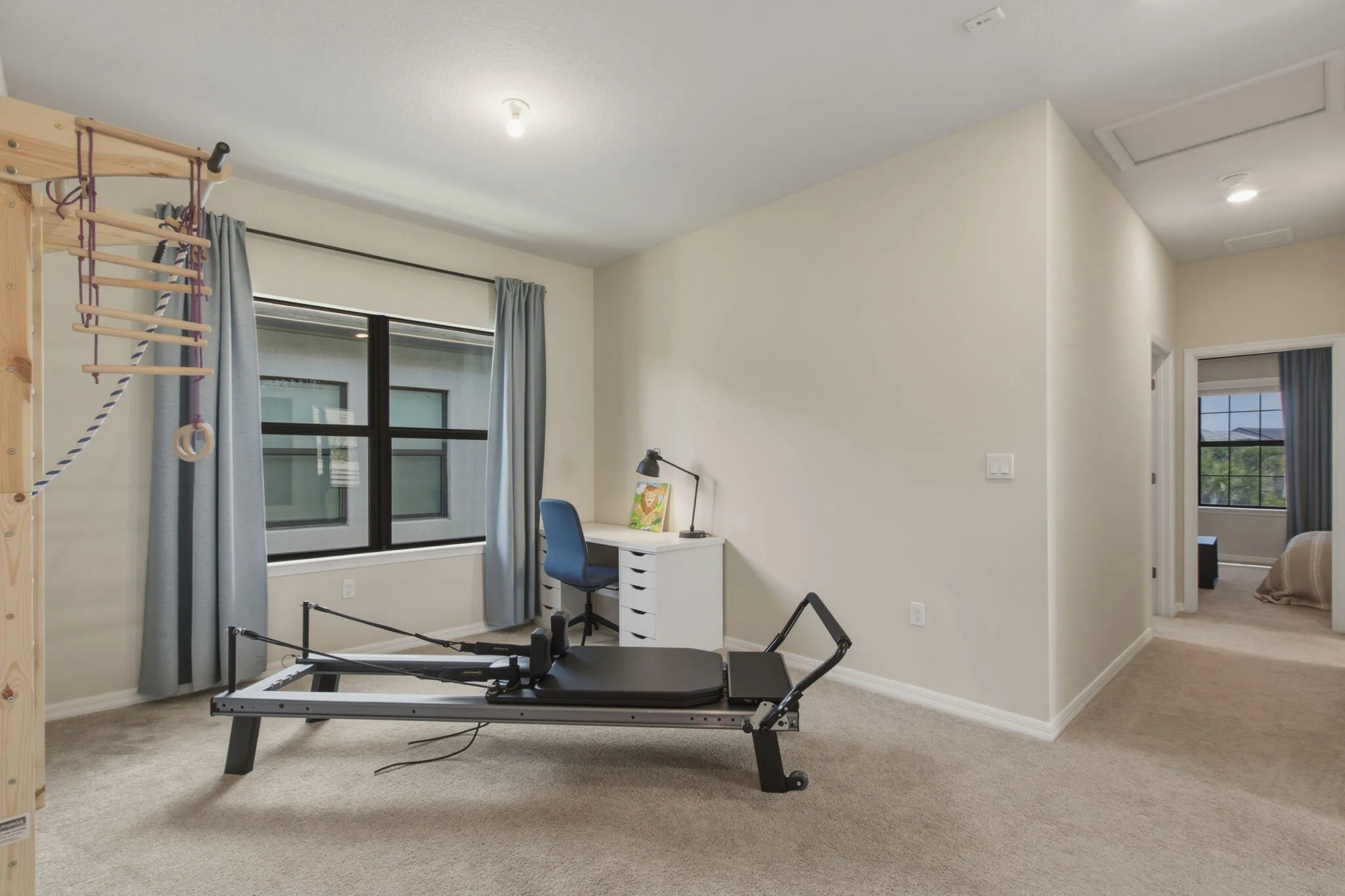 Spacious secondary room featuring neutral wall tones, plush carpeting, a large window with privacy blinds, and an overhead light fixture