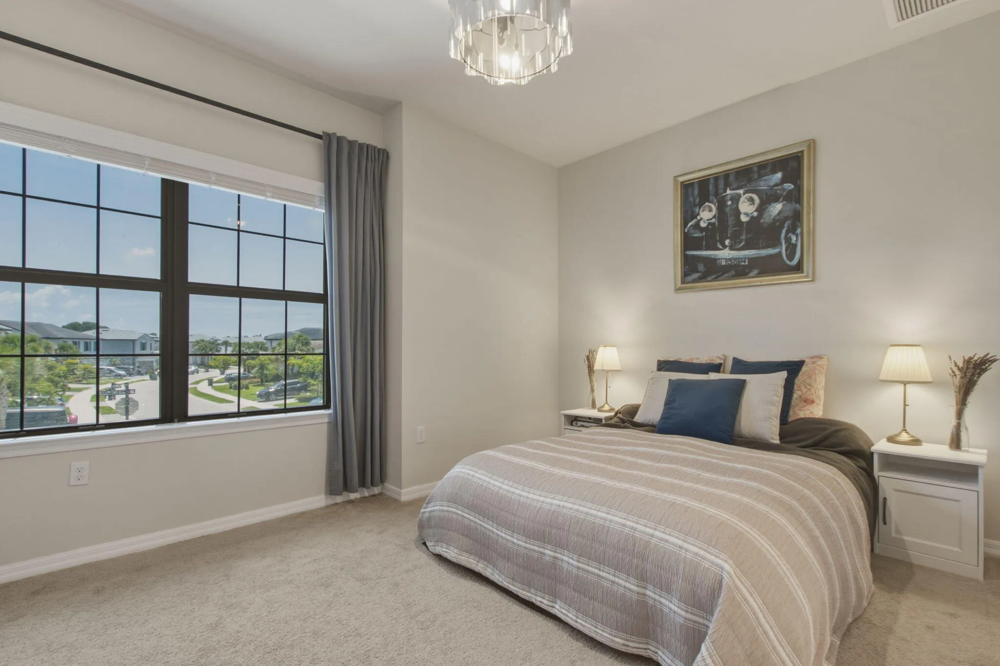 Spacious bedroom featuring neutral carpeting and a large grid-pattern window with a streetscape beyond