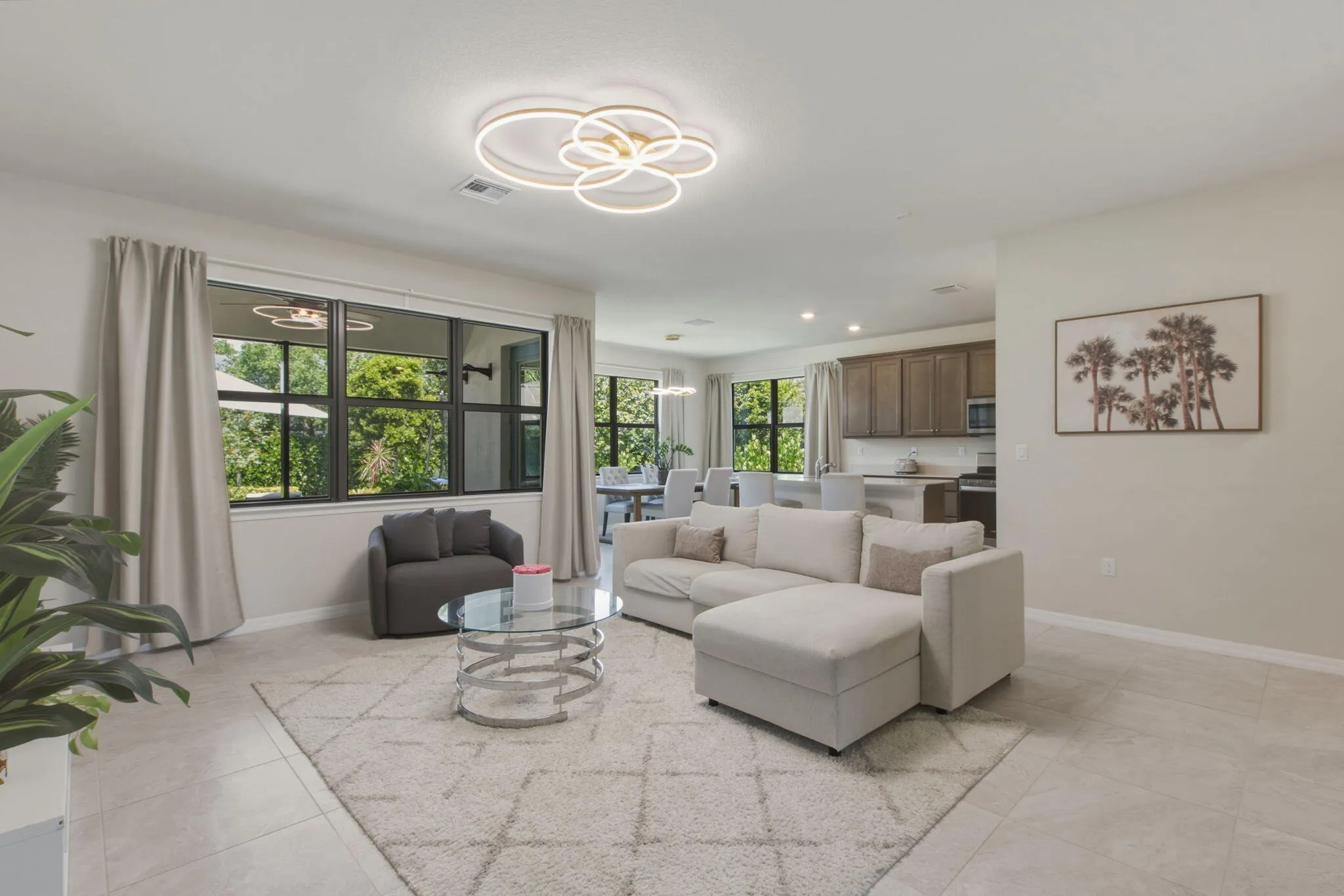 Open-concept living area with large windows, light tile flooring, and recessed lighting