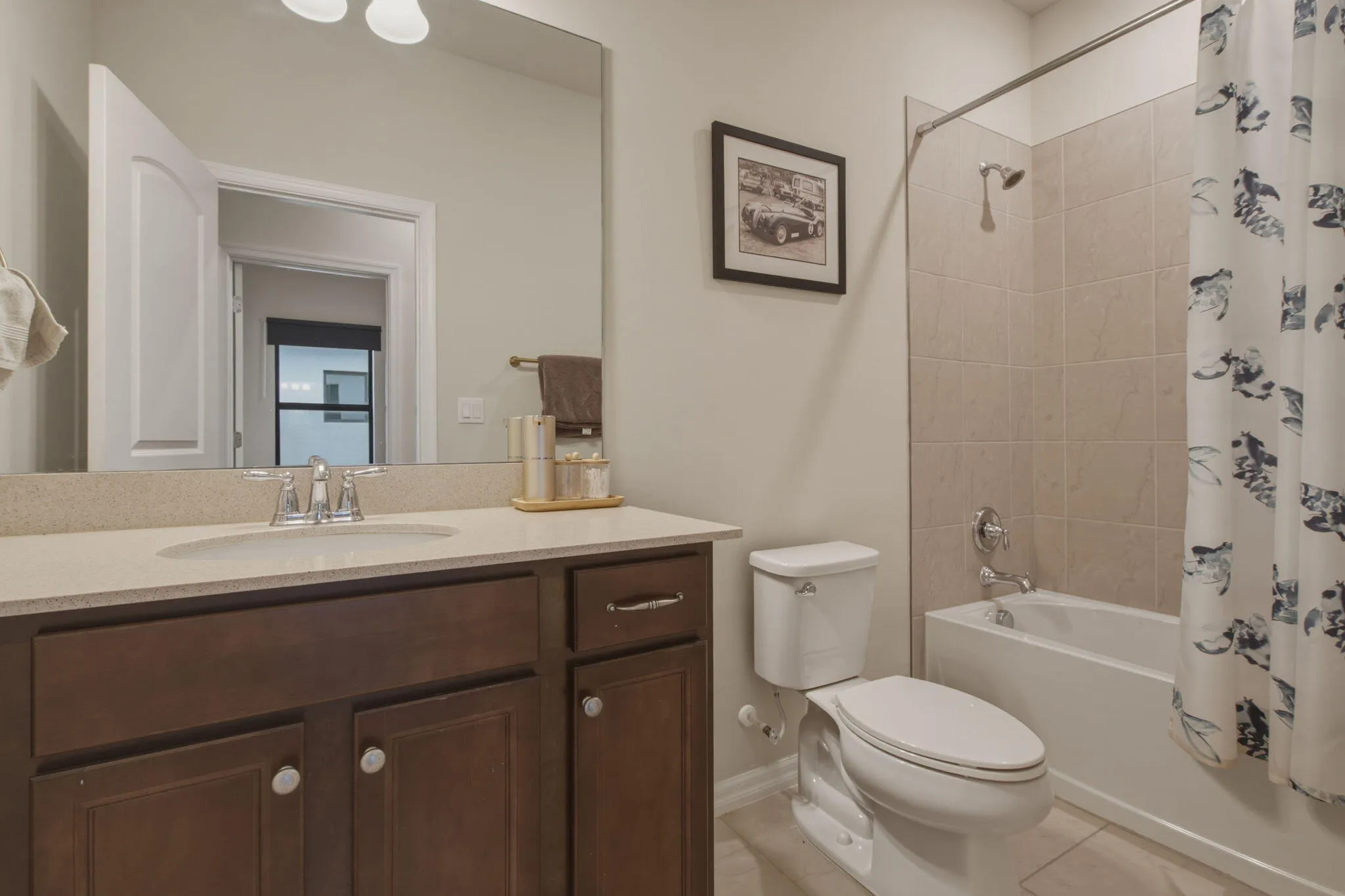 Bathroom vanity featuring a light-toned countertop, undermount sink, and dark wood-finish cabinetry