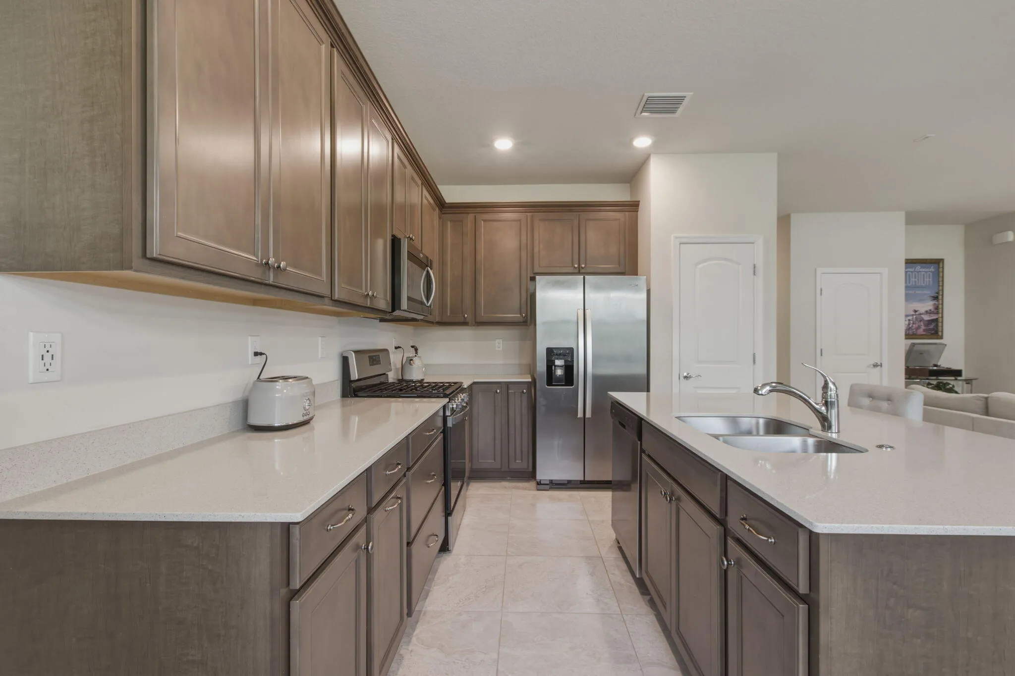 Kitchen featuring light wood-finish cabinetry with brushed nickel hardware, light-toned countertops, and stainless steel appliances