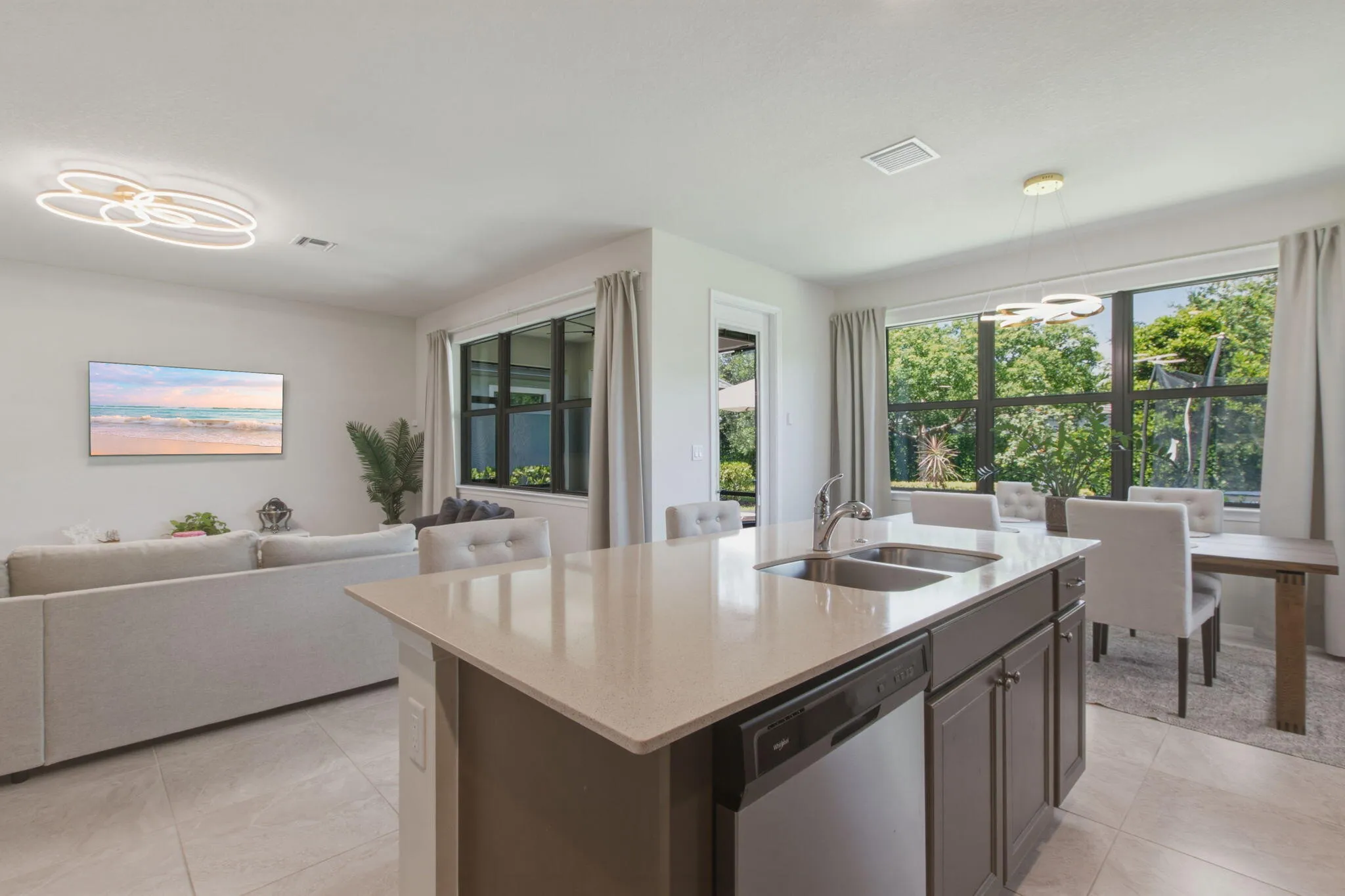 Kitchen island featuring a dual-basin stainless steel sink, integrated dishwasher, and light-toned countertop