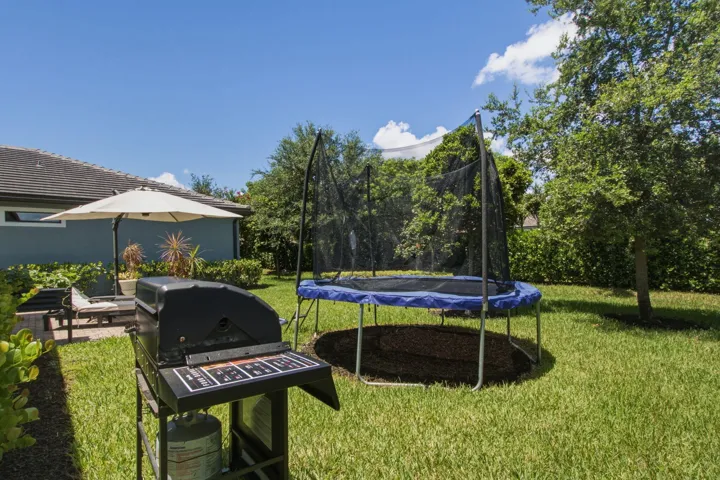 Expansive backyard featuring a manicured lawn, established trees, and a paver patio area