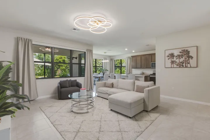 Open-concept living area with large windows, light tile flooring, and recessed lighting