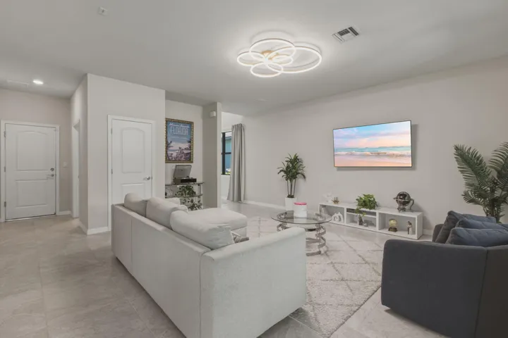 Open-concept living space with light-toned walls and large format tile flooring