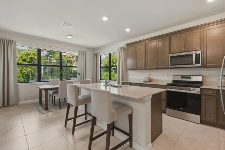 Open-concept kitchen and dining area featuring light-toned tile flooring, recessed lighting, and expansive windows
