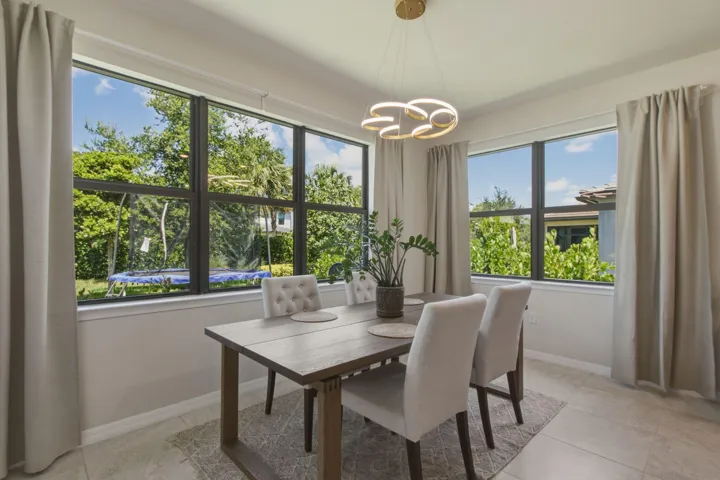 Dining area featuring large windows, a contemporary light fixture, tiled flooring, and neutral wall tones