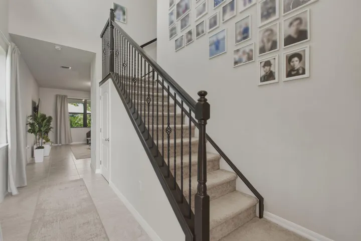 Staircase featuring dark iron balusters with decorative accents, carpeted treads, and a coordinating dark wood-finish newel post and handrail