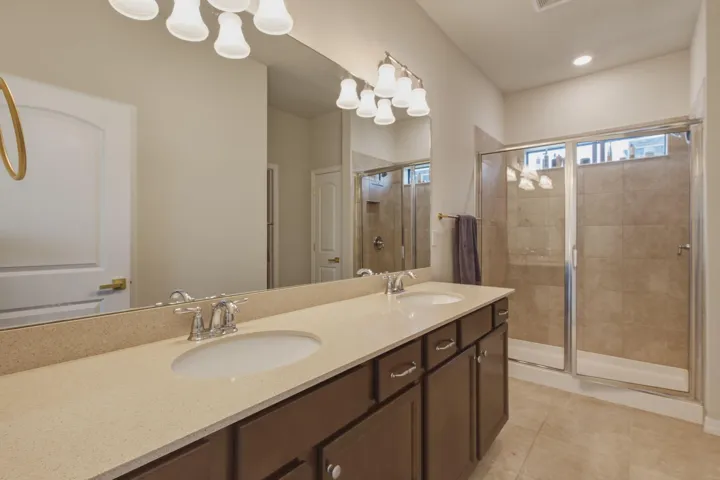Dual sink vanity with a light-colored countertop, dark wood-finish cabinetry, and chrome fixtures
