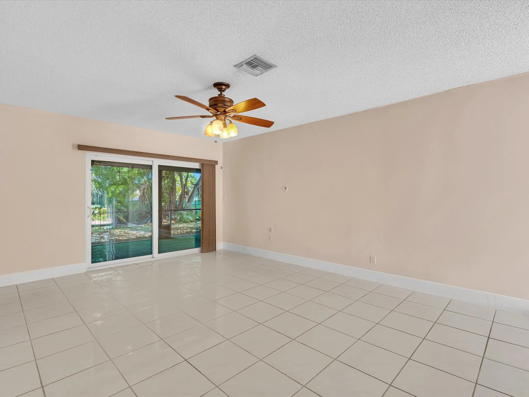 Spacious interior room featuring light-toned tile flooring throughout and a contemporary ceiling fan with integrated lighting