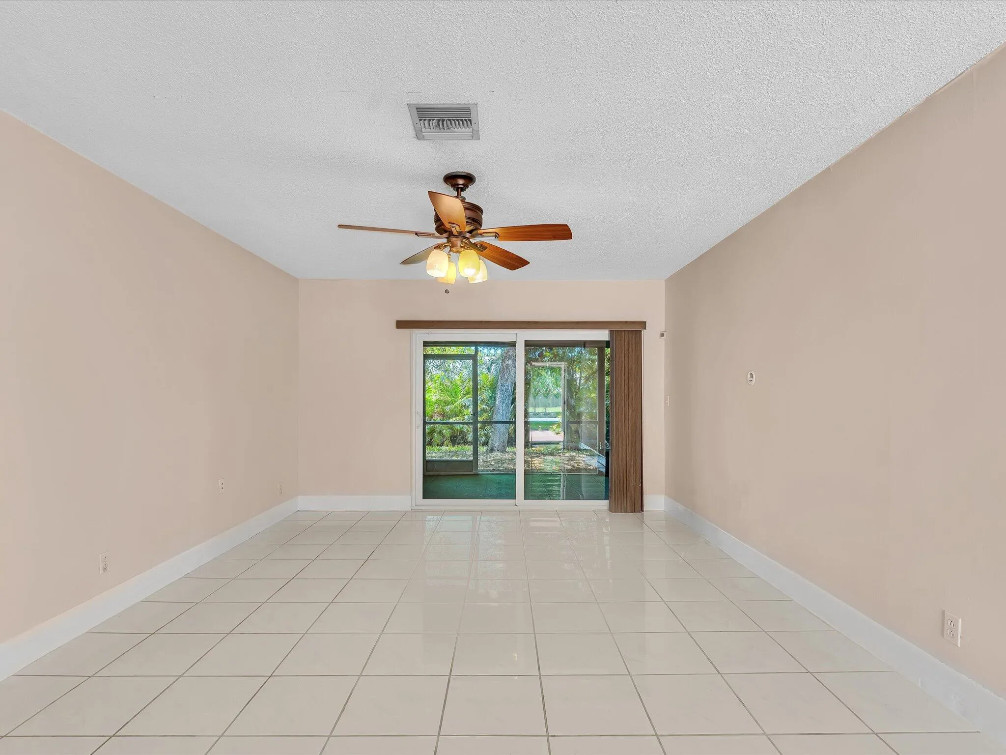 Spacious room featuring light-toned walls, white tile flooring, and a ceiling fan with integrated lighting