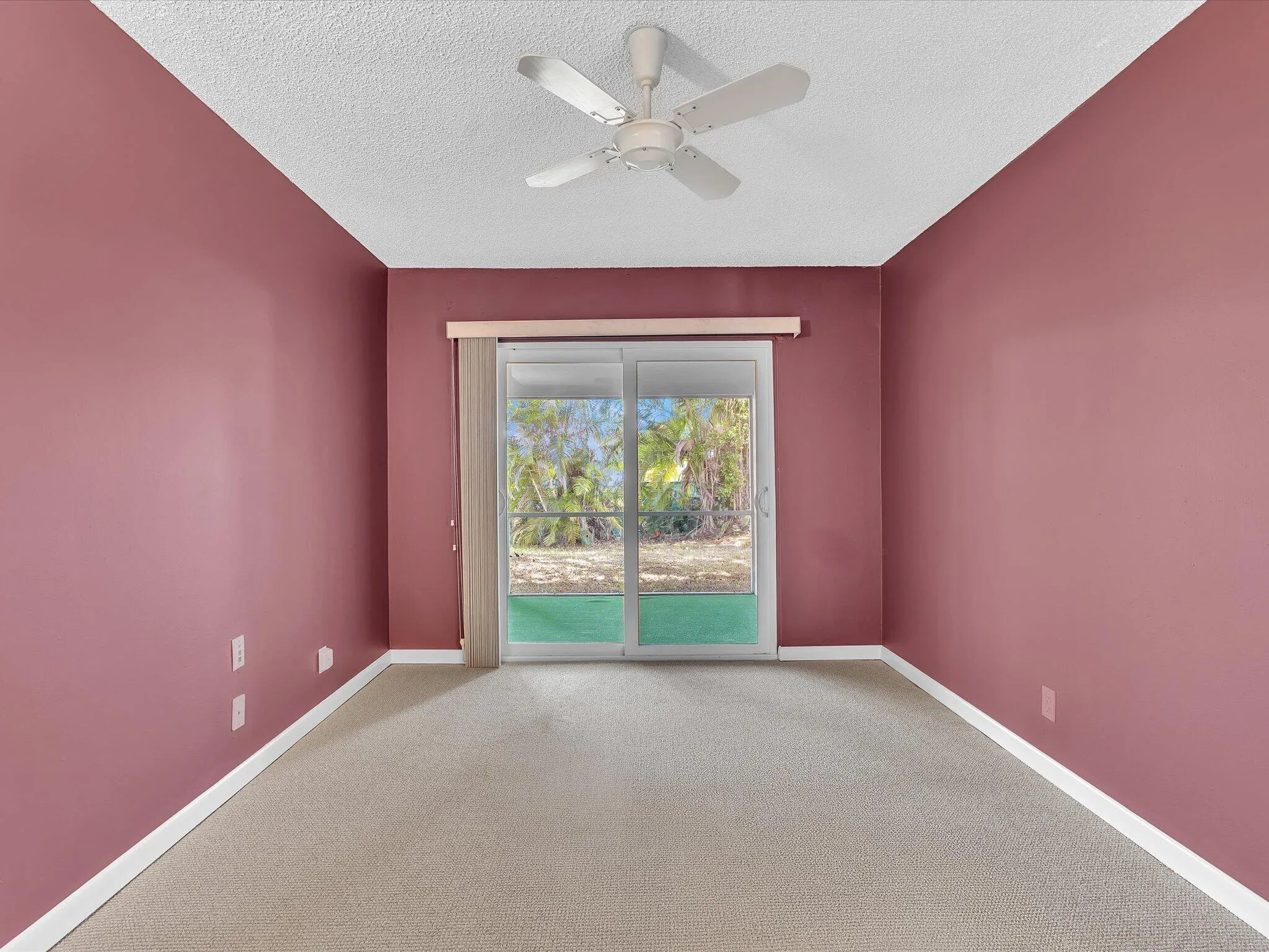 Sliding glass doors opening to outdoor scenery, textured ceiling, ceiling fan, and carpeted flooring
