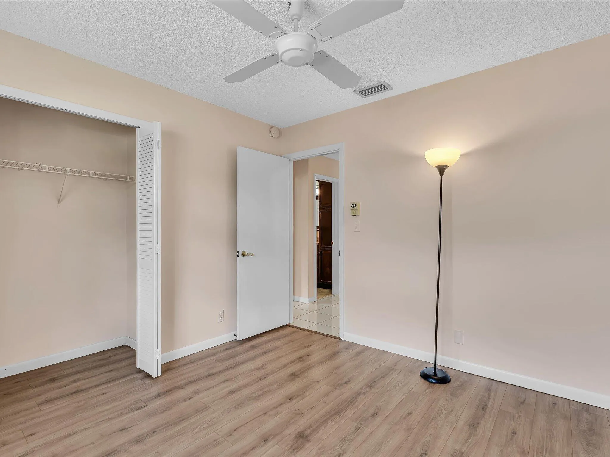 Room featuring wood-finish flooring, a ceiling fan, and a built-in closet with bifold louvered doors