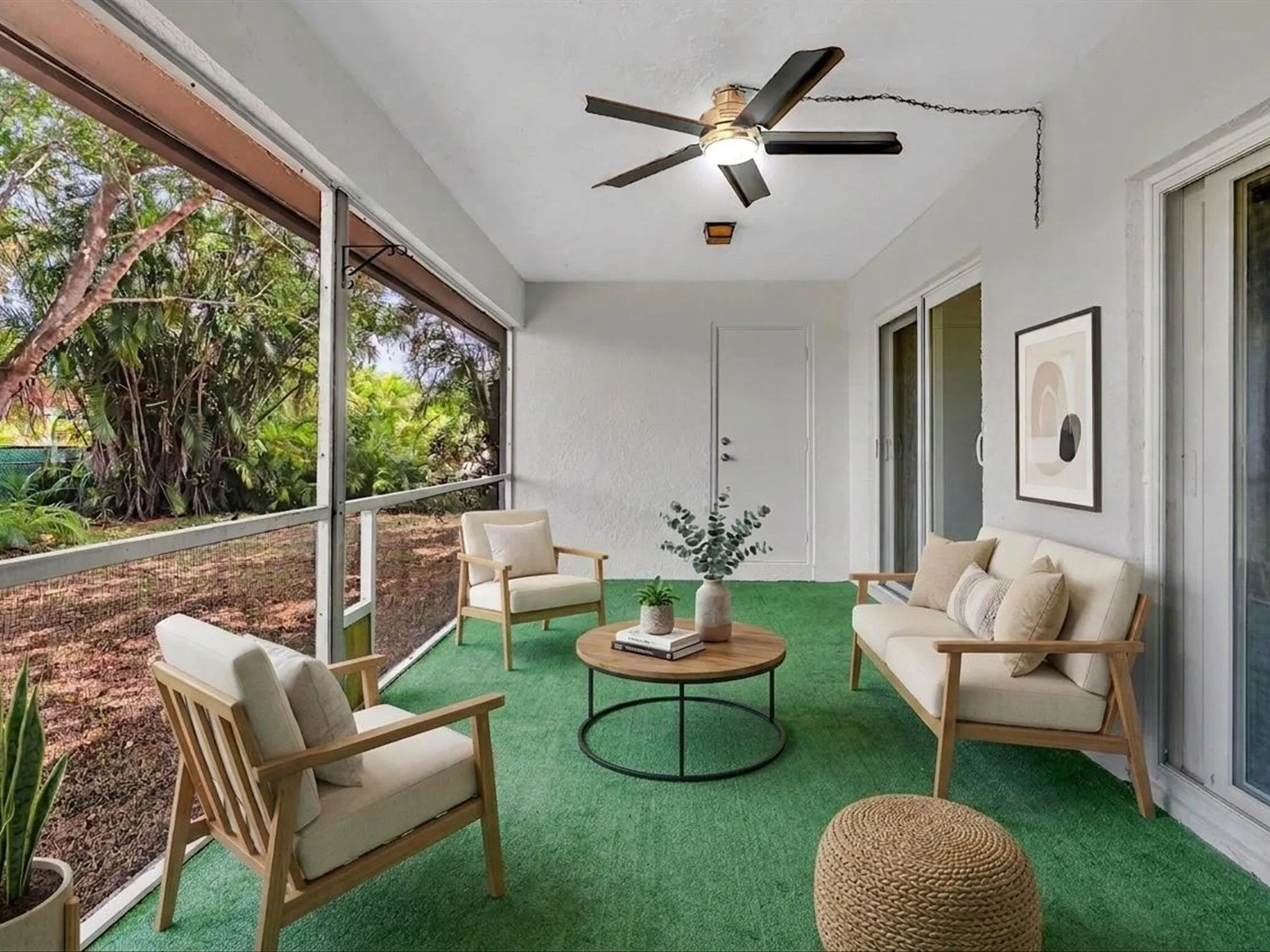 Screened outdoor patio featuring a ceiling fan and green artificial turf flooring