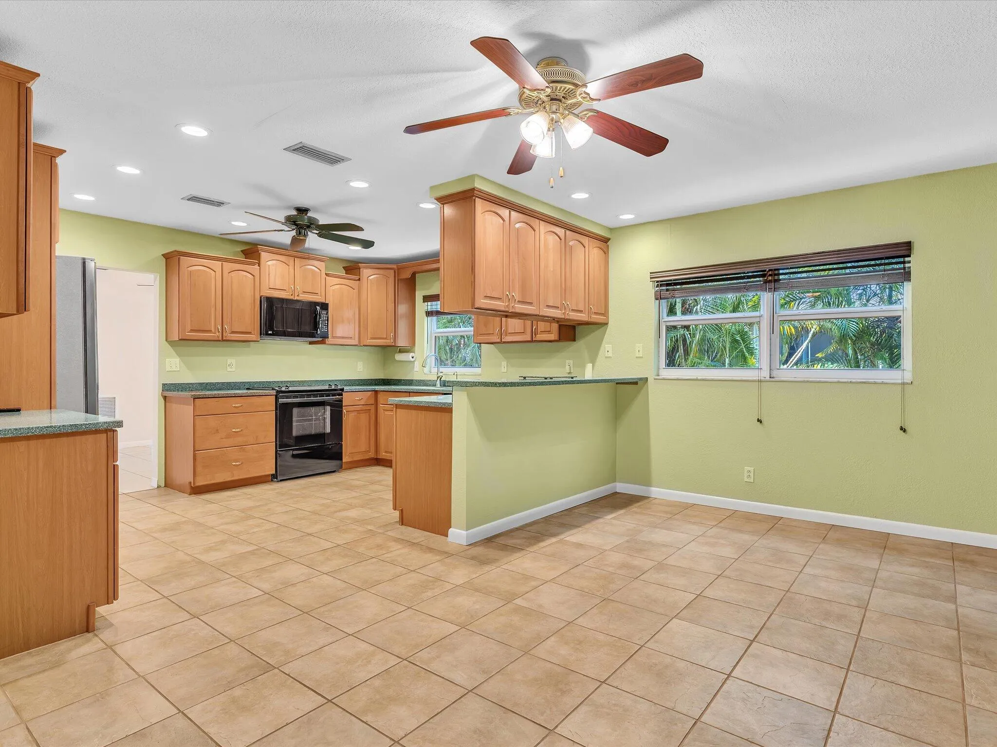Expansive kitchen featuring wood cabinetry, integrated appliances, recessed lighting, and ceiling fans