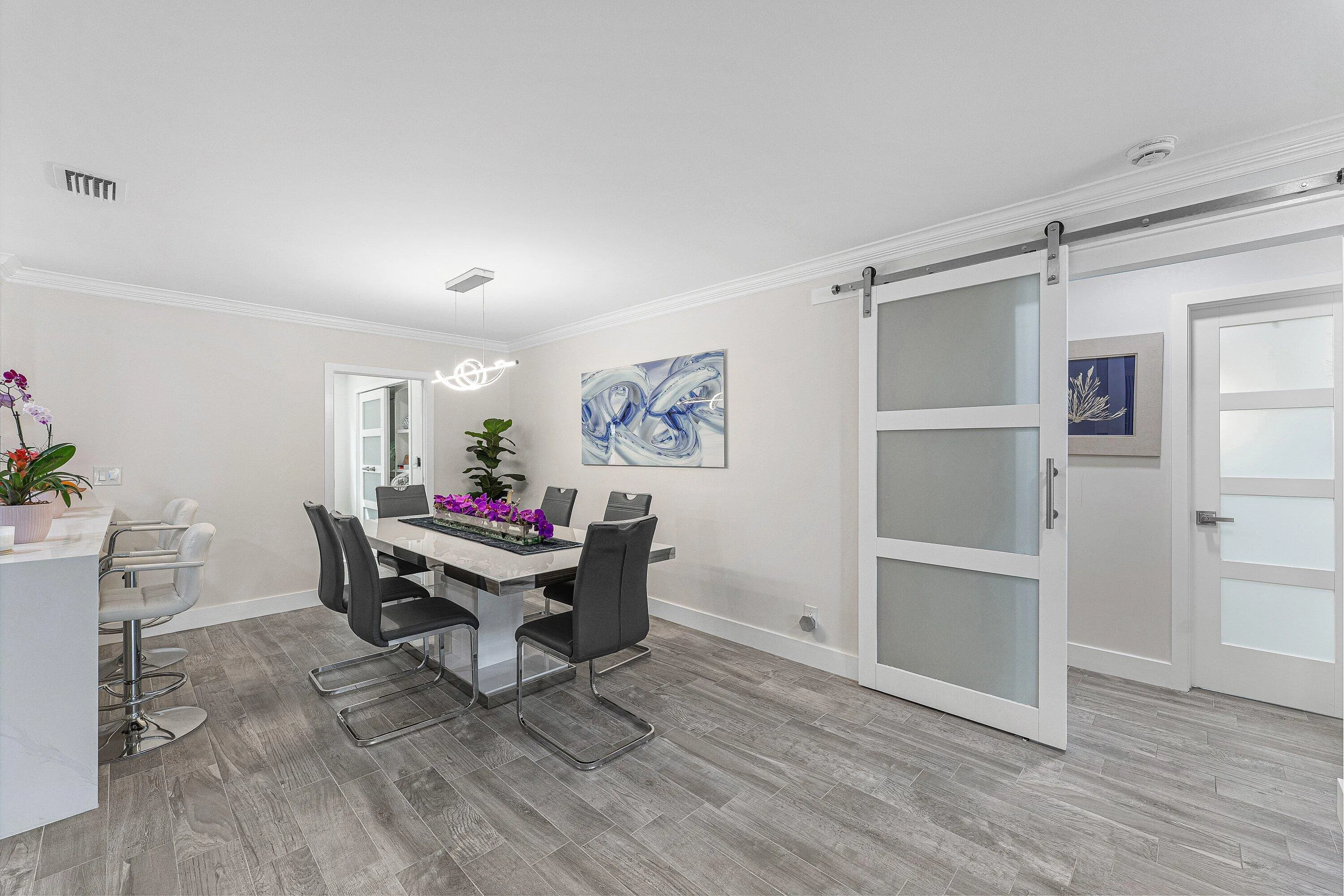 Spacious dining area featuring wood-finish flooring, crown molding, and a modern chandelier