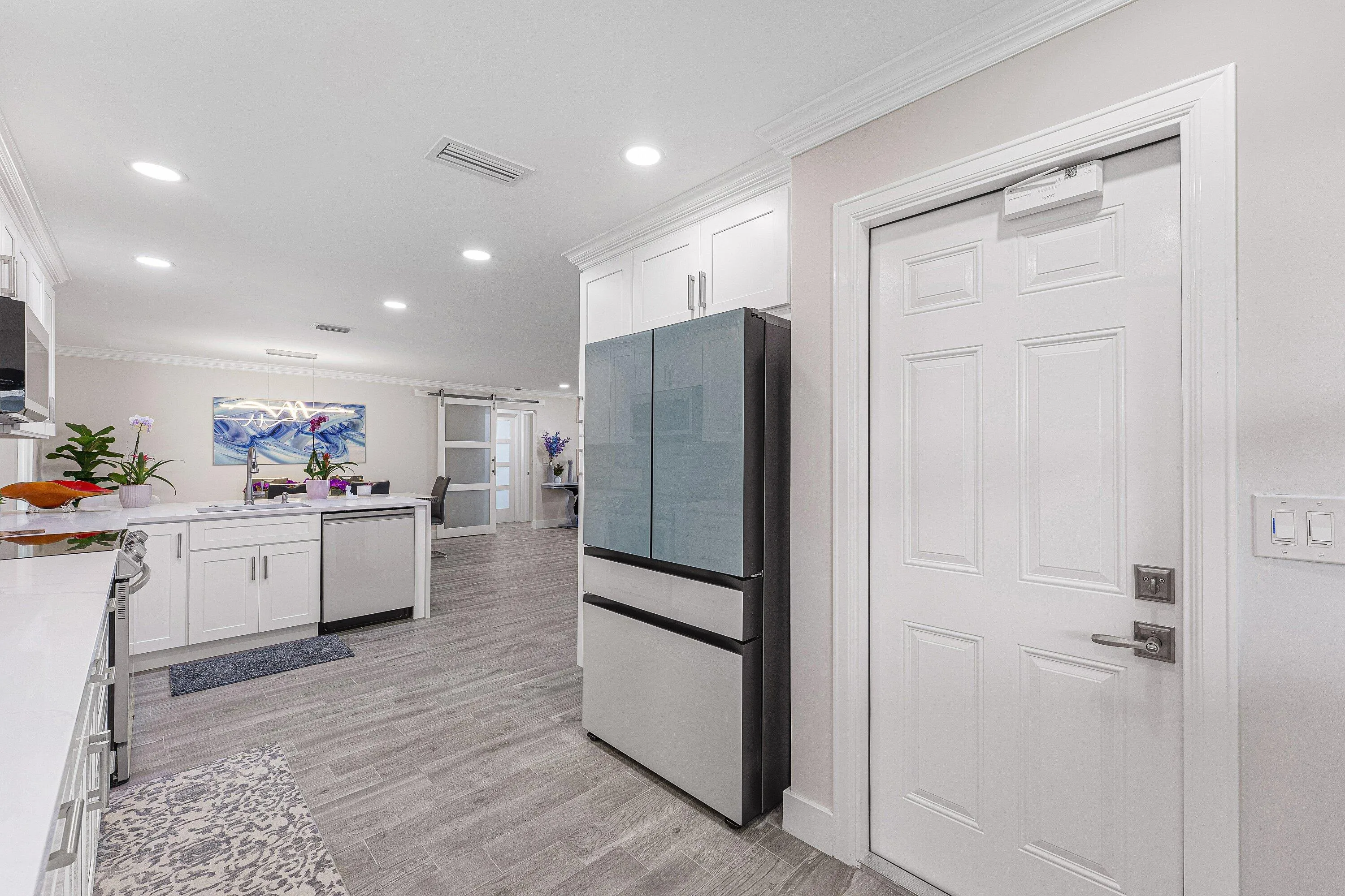 Bright kitchen featuring white cabinetry, light countertops, stainless steel appliances, wood-finish flooring, and recessed lighting