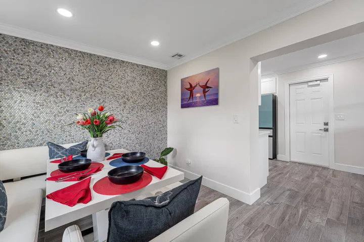 Dining area featuring a mosaic tile accent wall, recessed lighting, crown molding, and wood-finish flooring